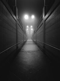 Empty footpath along illuminated wall