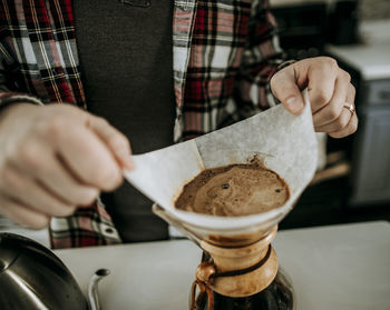 Man with wedding ring and flannel steadies pour over coffee filter