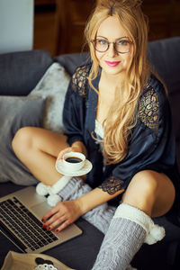 Portrait of young woman sitting on sofa at home