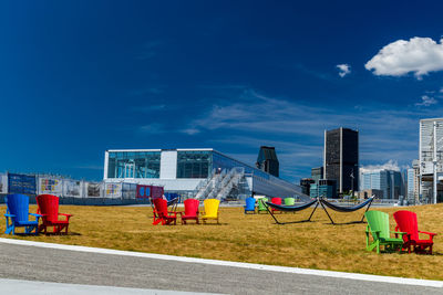 People on road by buildings against blue sky