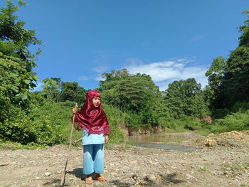 Full length of girl holding stick while standing against trees