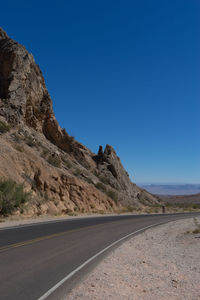 Road by mountains against clear blue sky