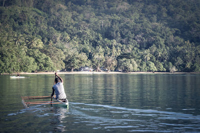 Man in boat on lake against trees