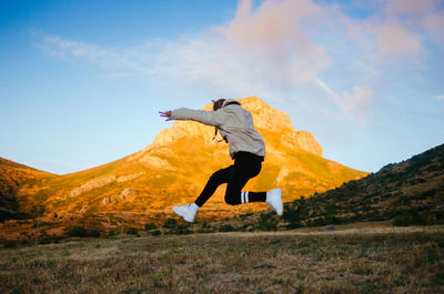 Back view of unrecognizable male in casual clothes jumping high