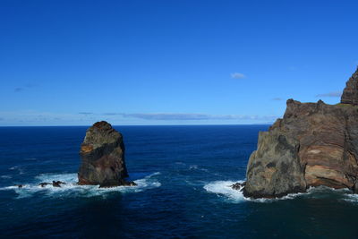 Rock formation in sea against blue sky