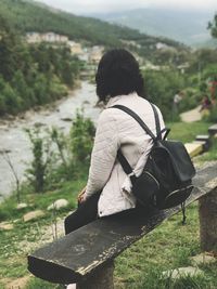 Rear view of woman sitting on bench