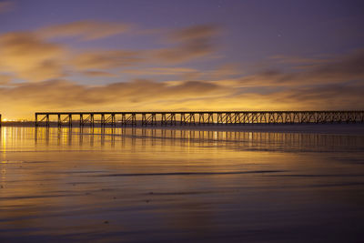 Bridge over sea against sky during sunset