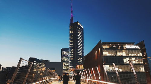 Low angle view of skyscrapers lit up against sky