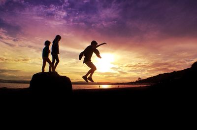 Silhouette of woman jumping at sunset