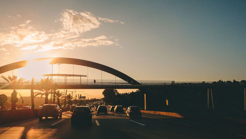 Silhouette bridge over river against sky at sunset