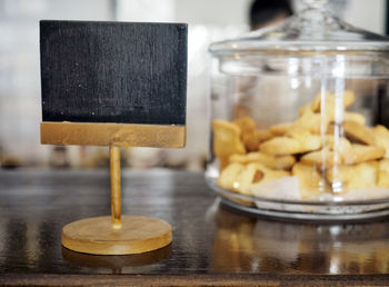 Close-up of blank blackboard by food jar on table at restaurant