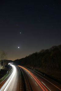 Light trails on highway against sky at night