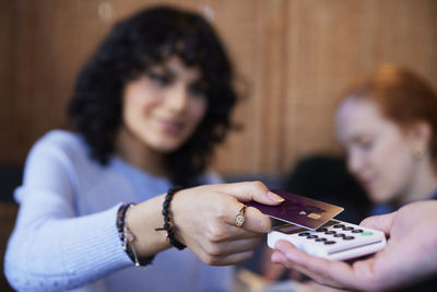 Young woman paying with card in cafe