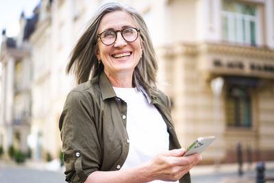 Portrait of young woman using mobile phone in city