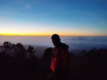 Rear view of silhouette man standing against sky during sunset