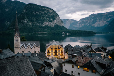 Houses by lake and mountains against sky