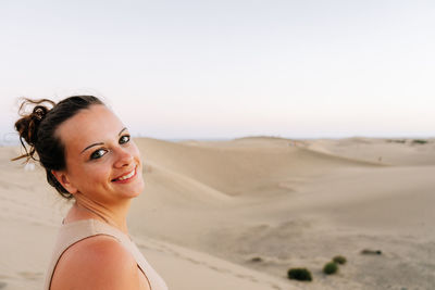 Portrait of young woman standing at desert