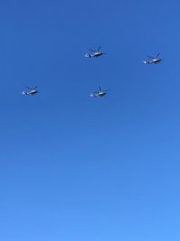 Low angle view of airplane flying against clear blue sky