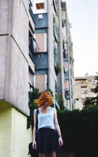 Woman standing by building in city