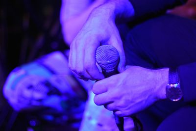 Midsection of man holding microphone at nightclub