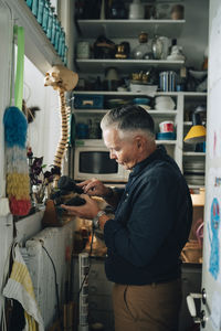 Side view of senior male owner examining antiques at store