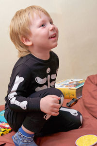 Portrait of boy looking away while sitting on sofa at home