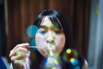 Young woman blowing bubbles at home
