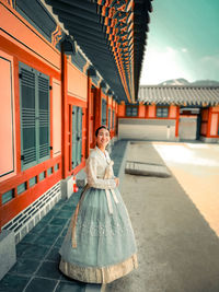 Portrait of young woman standing in front of building