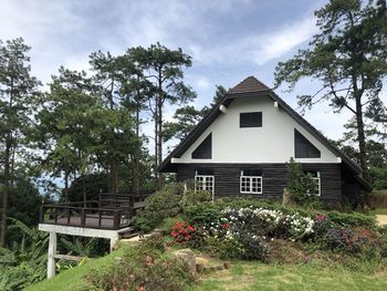 House and trees by building against sky