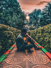 Man photographing while sitting by tree