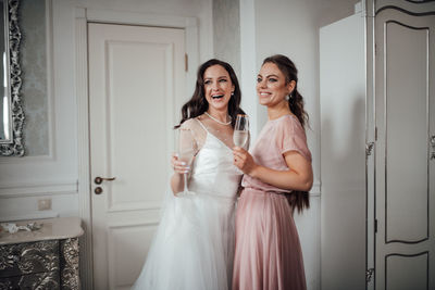 Bridesmaid and bride holding champagne flute