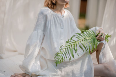 Midsection of woman sitting in white dress