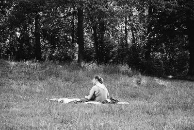 Full length of man sitting on field in forest