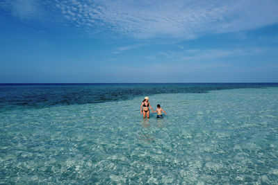 Mother and son walking on the indian ocean . aerial view