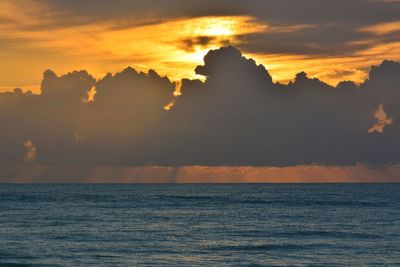 Scenic view of sea against cloudy sky during sunset