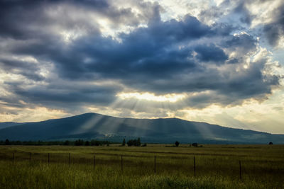 Scenic view of dramatic landscape against storm clouds