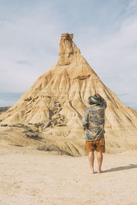 Rear view of woman standing on sand at beach against sky