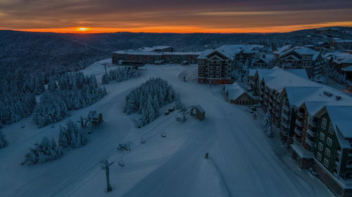 High angle view of snow covered houses and mountains against sky at sunset