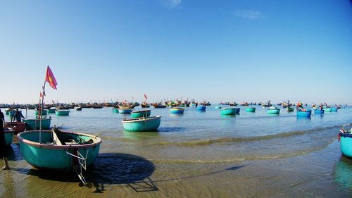 Boats moored on sea against clear blue sky