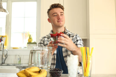 Young man holding ice cream at home