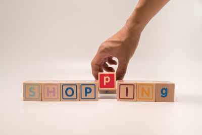 Cropped hand holding toy blocks against white background