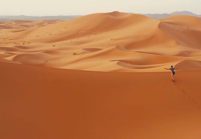 Excided man with spread arms in orange desert