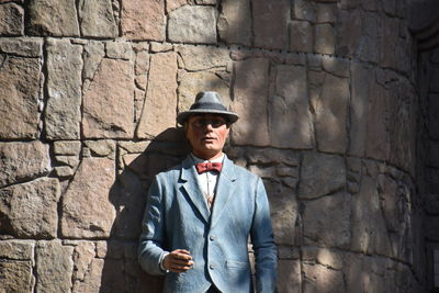 Portrait of mature man standing against brick wall