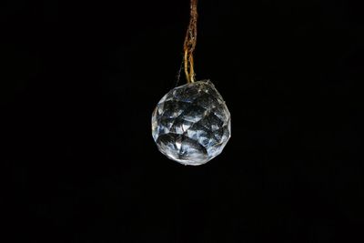 Close-up of crystal ball hanging against black background
