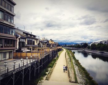 People walking on footbridge against sky