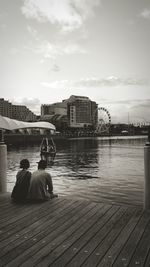 Couple sitting on pier at sea