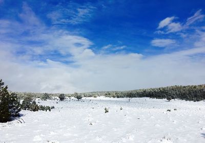 Snow covered landscape against cloudy sky