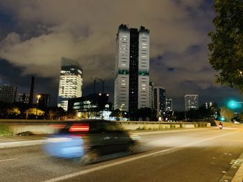 City street by illuminated buildings against sky at night