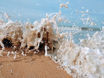 Close-up of splashing water at beach against sky