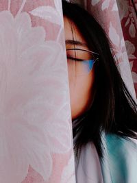 Close-up of woman wearing eyeglasses amidst curtains